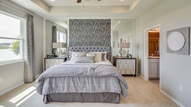 carpeted bedroom featuring a raised ceiling, ensuite bath, ceiling fan, and sink