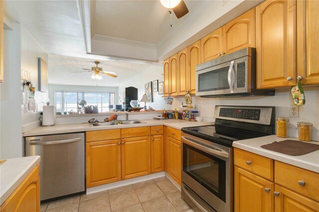 kitchen with sink, light tile patterned floors, ceiling fan, stainless steel appliances, and ornamental molding