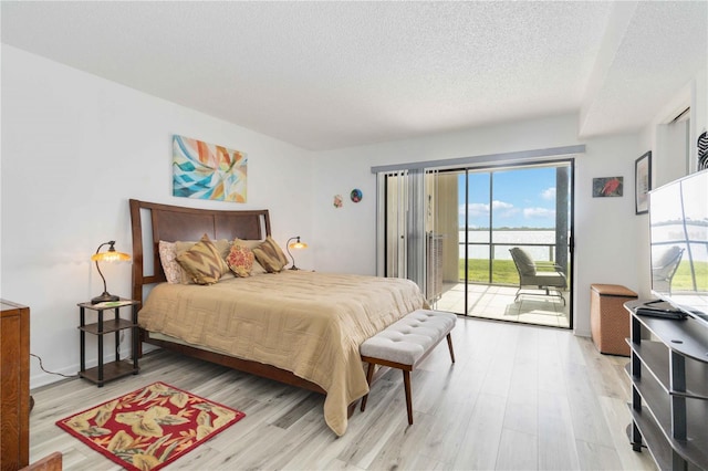 bedroom with access to outside, a textured ceiling, and light wood-type flooring