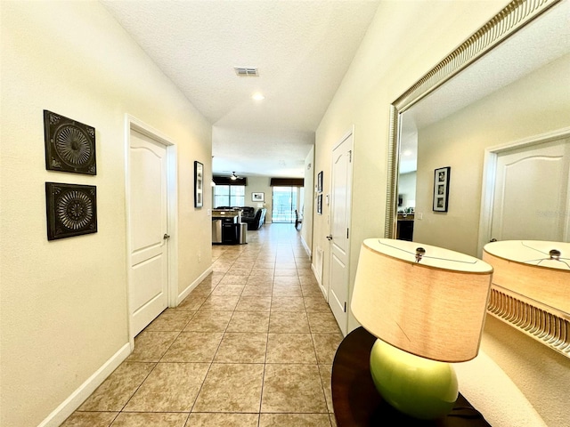 corridor with a textured ceiling and light tile patterned floors