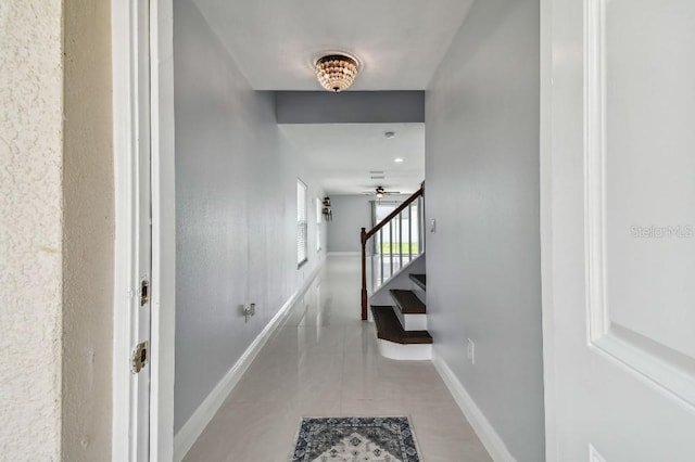 hallway with stairway, tile patterned flooring, and baseboards