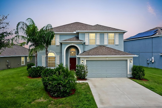 view of front of house featuring a garage, solar panels, and a lawn