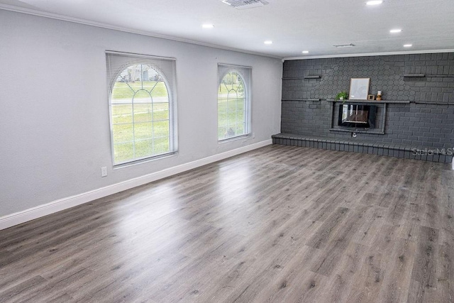 unfurnished living room featuring wood-type flooring, crown molding, and brick wall