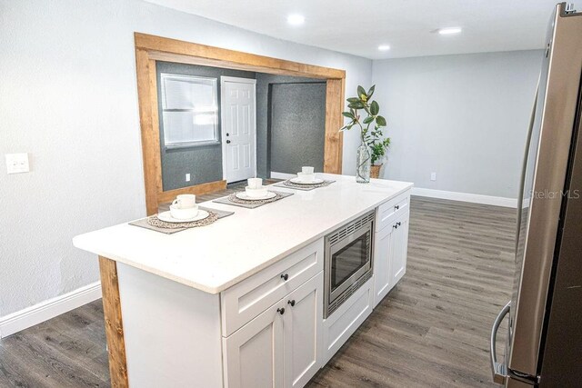 kitchen featuring dark hardwood / wood-style flooring, white cabinetry, a kitchen island, and stainless steel appliances