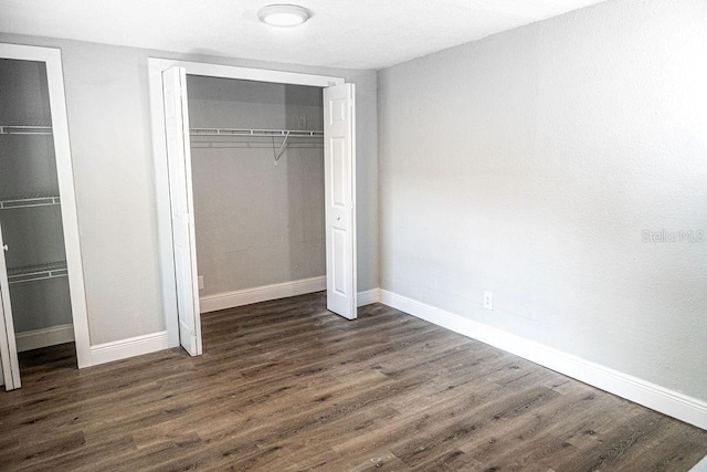 unfurnished bedroom with dark wood-type flooring and a closet