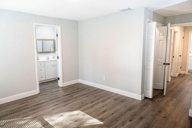 unfurnished bedroom with sink, connected bathroom, and dark hardwood / wood-style floors