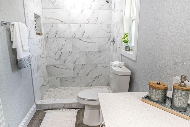 bathroom featuring tiled shower, toilet, and vanity