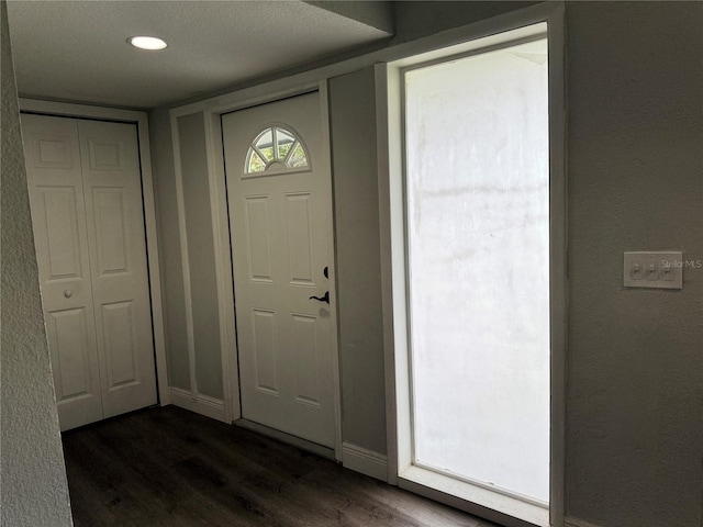 foyer featuring baseboards, a textured wall, recessed lighting, and dark wood-style flooring