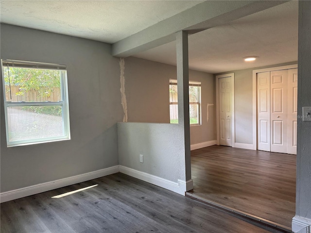 unfurnished room with baseboards, wood finished floors, and a textured ceiling