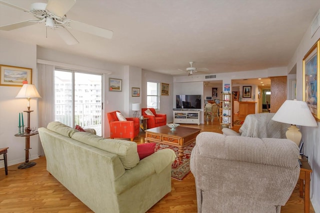 living room featuring light wood-type flooring, ceiling fan, and plenty of natural light