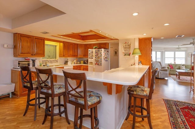 1 John Anderson Dr Unit 604, Ormond Beach, FL 32176 - kitchen with a tray ceiling, light wood-type flooring, a peninsula, and white appliances