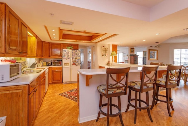 1 John Anderson Dr Unit 604, Ormond Beach, FL 32176 - kitchen with a tray ceiling, white appliances, light countertops, and light wood-style floors