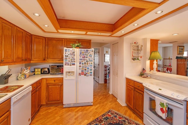 kitchen featuring light wood-type flooring, a tray ceiling, and white appliances