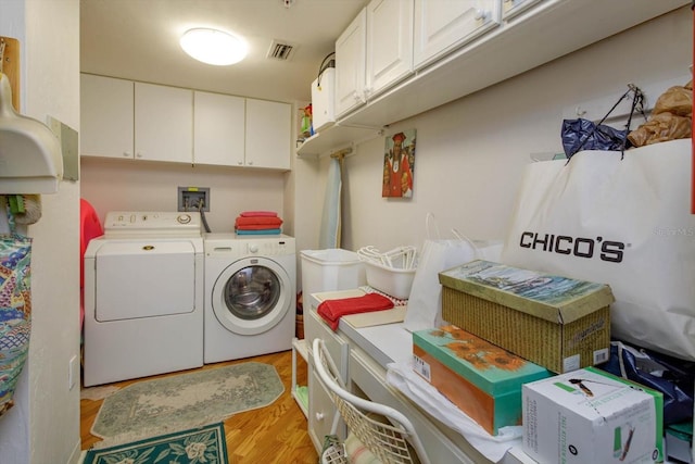 1 John Anderson Dr Unit 604, Ormond Beach, FL 32176 - clothes washing area featuring visible vents, washing machine and clothes dryer, cabinet space, and light wood-type flooring