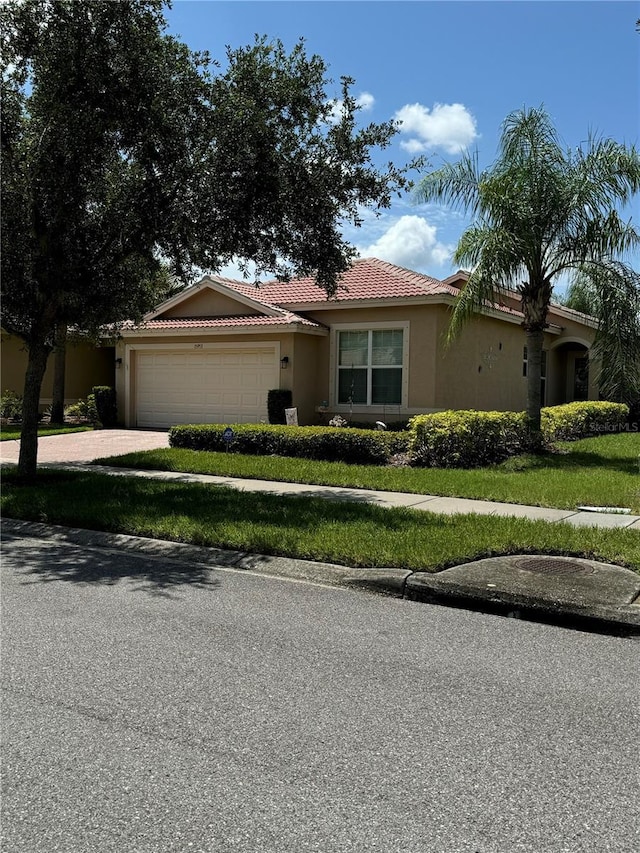 view of front of house featuring a garage, a tile roof, driveway, and stucco siding