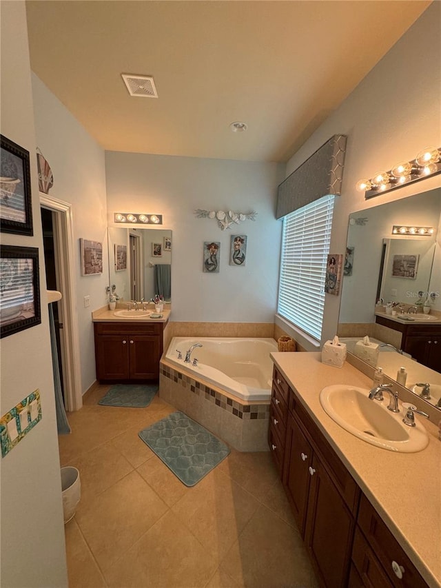 bathroom with a relaxing tiled tub, double vanity, and tile patterned floors