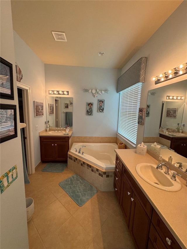 full bath featuring a garden tub, tile patterned flooring, two vanities, visible vents, and a sink