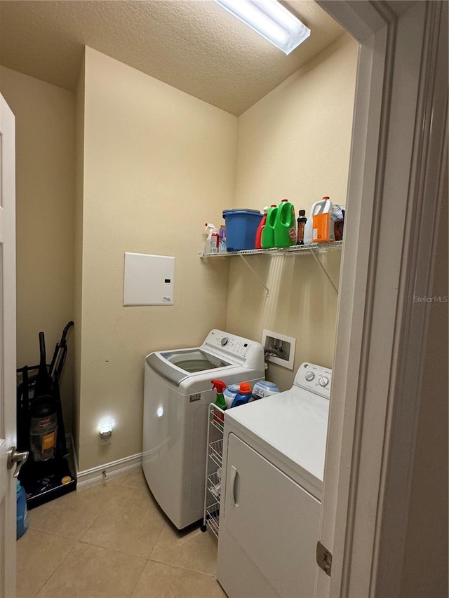 washroom with light tile patterned flooring, a textured ceiling, and independent washer and dryer