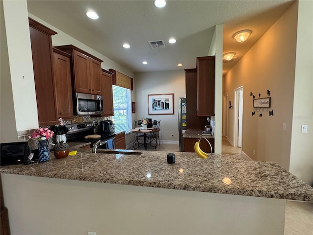 15953 Cobble Mill Dr, Wimauma, FL 33598 - kitchen with appliances with stainless steel finishes, light stone counters, recessed lighting, a peninsula, and backsplash