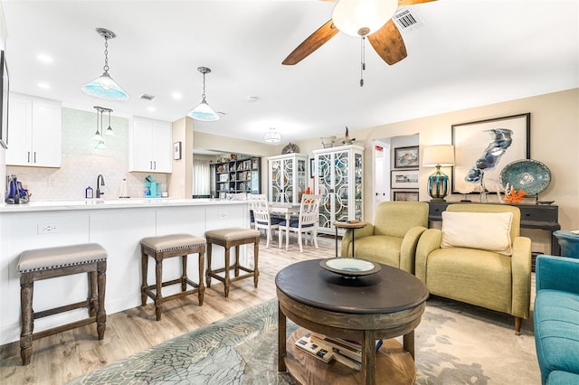 living room featuring sink, ceiling fan, and light hardwood / wood-style flooring