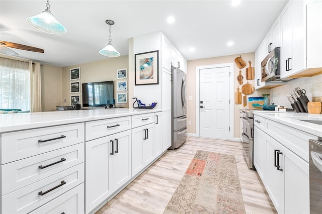 kitchen featuring white cabinets, pendant lighting, and appliances with stainless steel finishes