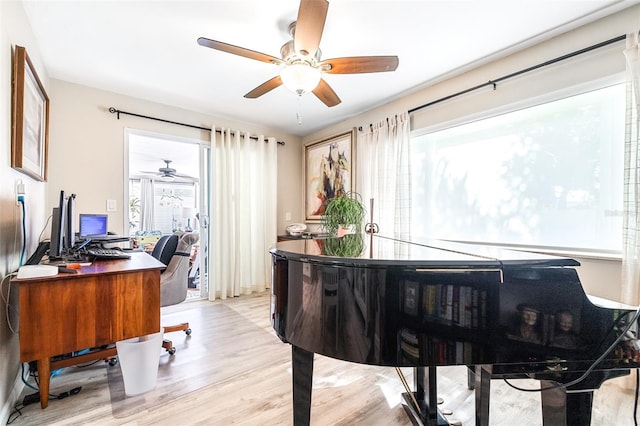 office area with light hardwood / wood-style floors, ceiling fan, and a healthy amount of sunlight