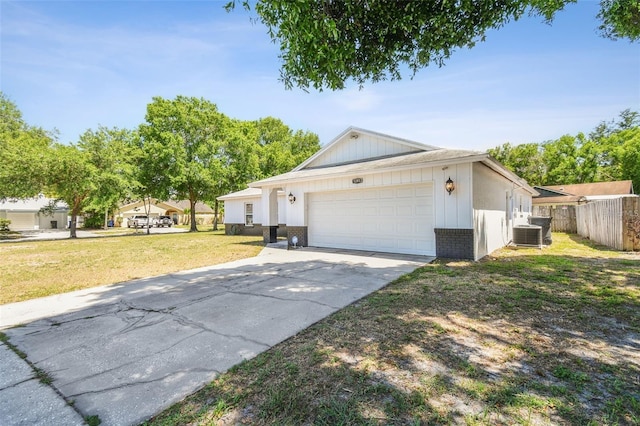 ranch-style home featuring a garage, central air condition unit, and a front yard