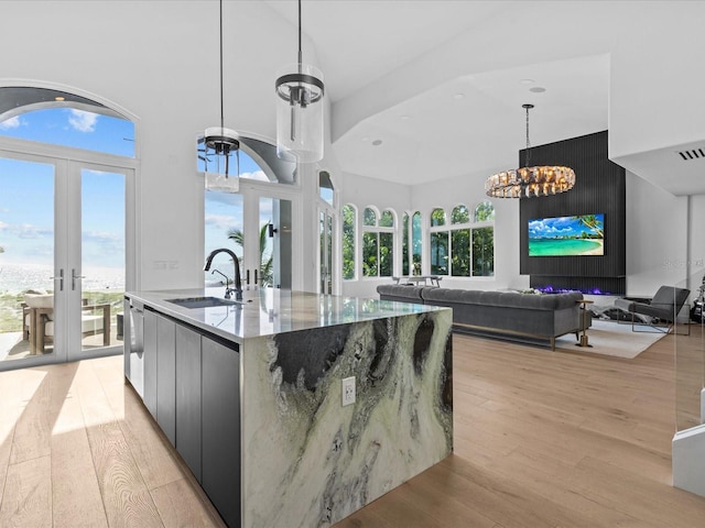 kitchen featuring sink, hanging light fixtures, a large island, light wood-type flooring, and french doors