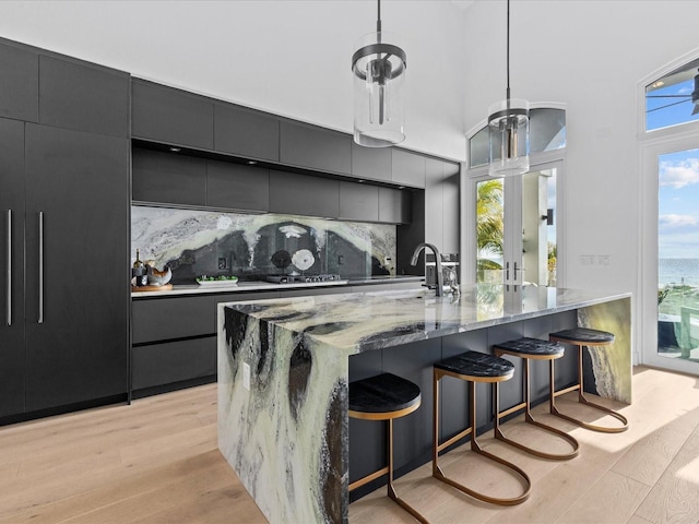 kitchen featuring hanging light fixtures, decorative backsplash, light hardwood / wood-style floors, and a spacious island