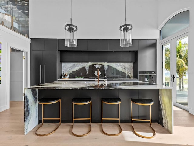 kitchen with tasteful backsplash, pendant lighting, light hardwood / wood-style floors, and french doors