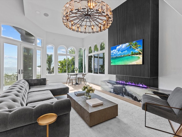 living room featuring a water view, a healthy amount of sunlight, french doors, and a notable chandelier