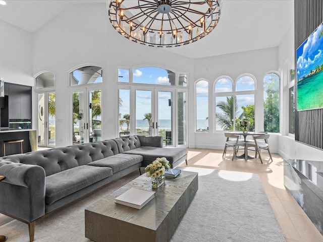 sunroom / solarium featuring lofted ceiling, french doors, a chandelier, and a water view