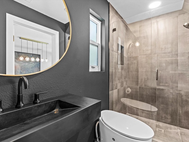 bathroom featuring toilet, a shower with shower door, and sink