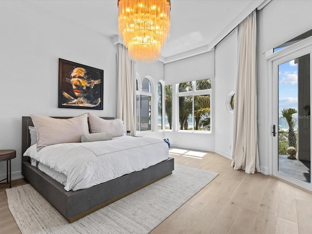 bedroom featuring an inviting chandelier, hardwood / wood-style flooring, and access to outside