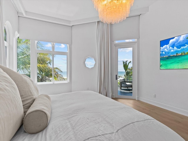 bedroom featuring multiple windows, hardwood / wood-style flooring, access to outside, and an inviting chandelier