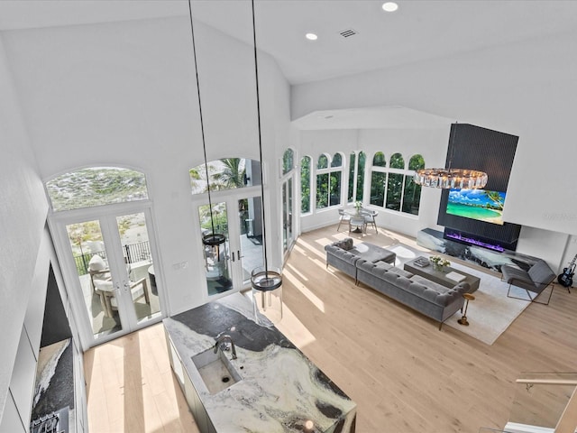 living room featuring sink, wood-type flooring, high vaulted ceiling, and french doors