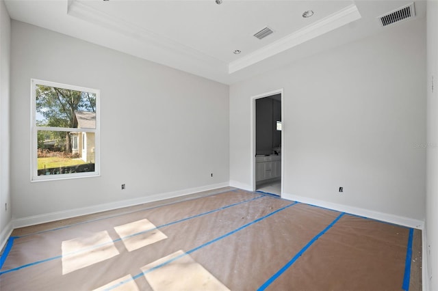 unfurnished bedroom with ornamental molding, ensuite bathroom, and a raised ceiling