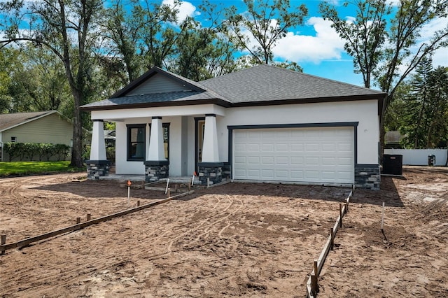 view of front of house featuring covered porch, a garage, and central AC unit