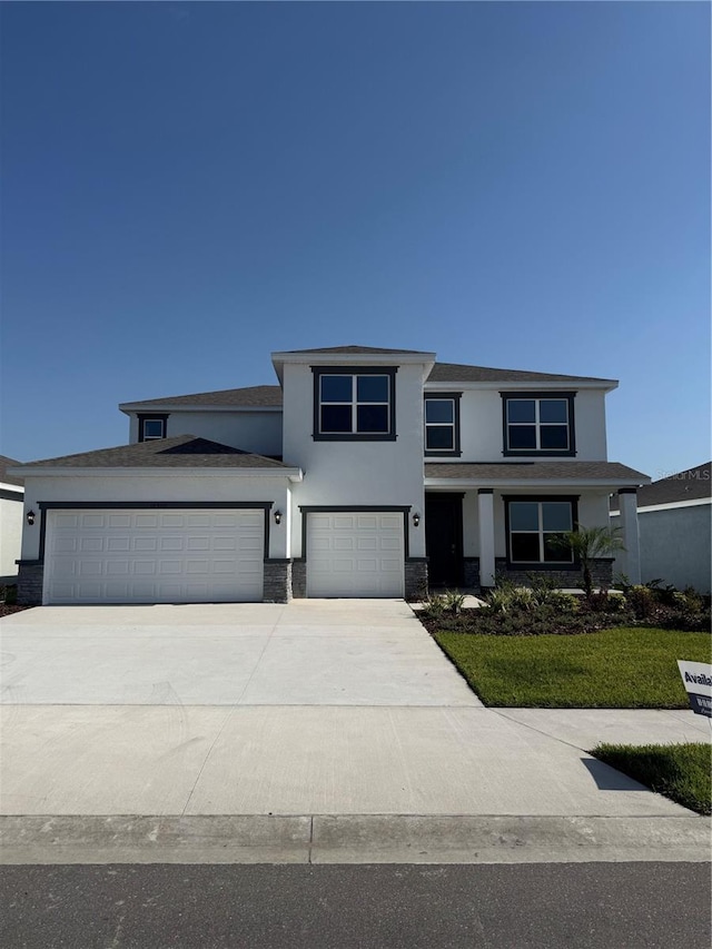 prairie-style house with stucco siding, driveway, an attached garage, and a front yard