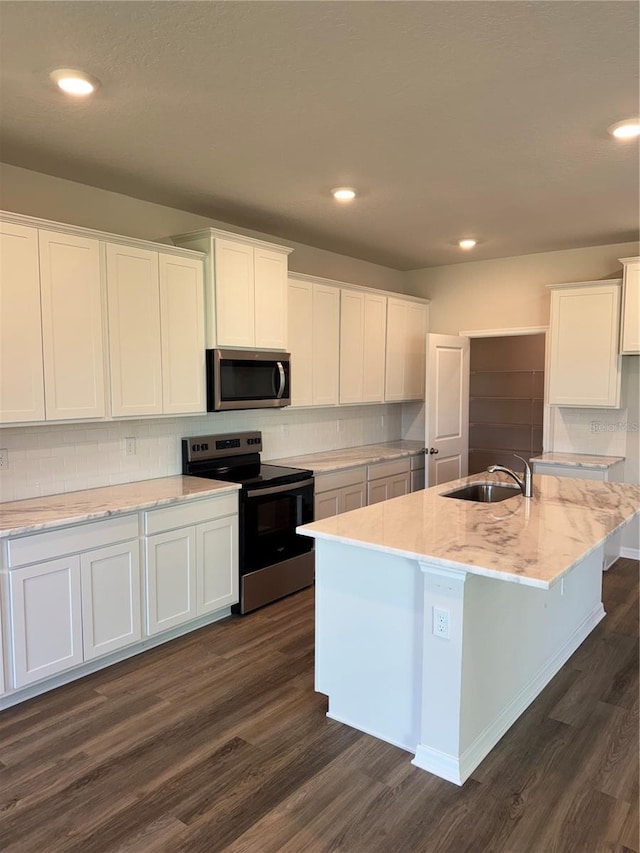 kitchen with stainless steel appliances, a sink, white cabinets, dark wood finished floors, and recessed lighting