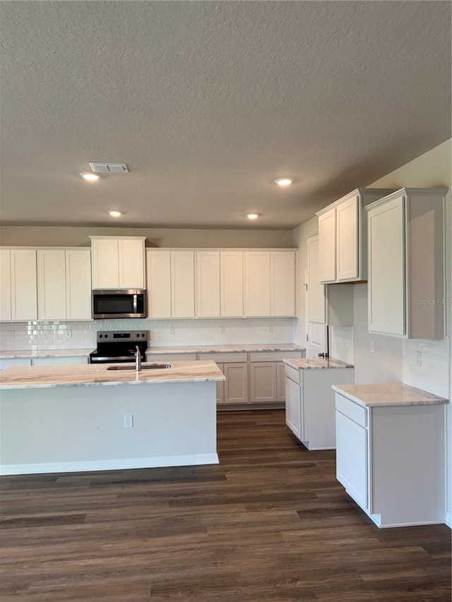 kitchen featuring appliances with stainless steel finishes, dark wood-type flooring, a textured ceiling, tasteful backsplash, and a sink