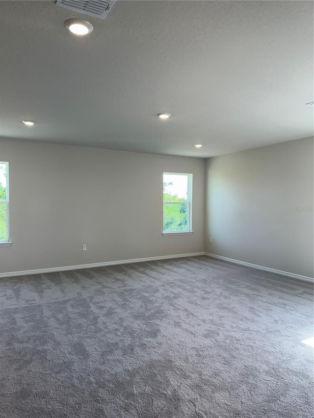 unfurnished room with dark colored carpet, baseboards, recessed lighting, and a textured ceiling