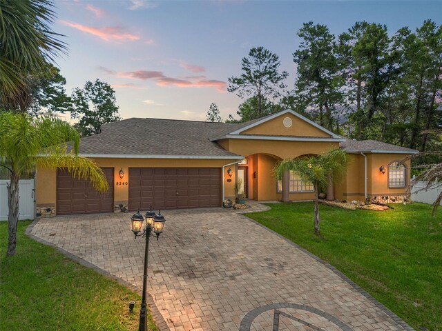 single story home with a garage and a lawn