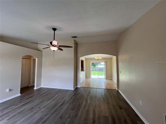 empty room with hardwood / wood-style flooring, ceiling fan with notable chandelier, and lofted ceiling