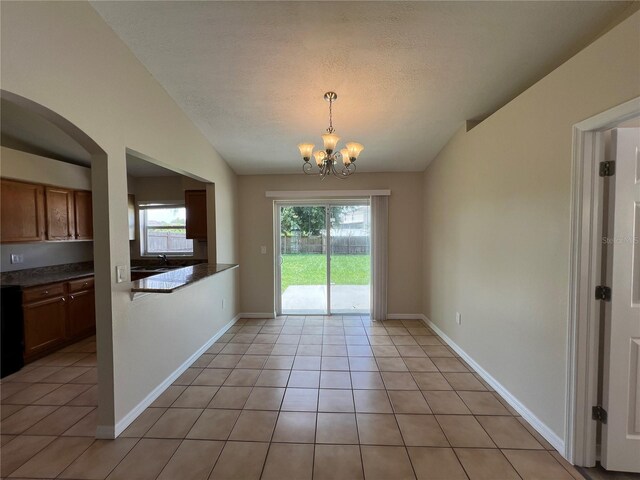 empty room with lofted ceiling, a notable chandelier, and light tile patterned floors