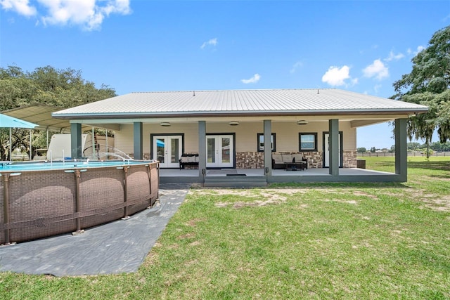 rear view of house with an outdoor living space, a patio, a lawn, and french doors