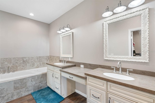 bathroom featuring a relaxing tiled tub, vanity, and wood-type flooring