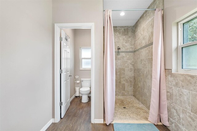 bathroom featuring hardwood / wood-style floors, curtained shower, a wealth of natural light, and toilet