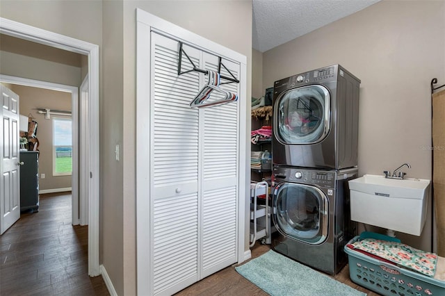 laundry area with dark hardwood / wood-style flooring, sink, a textured ceiling, and stacked washer / dryer