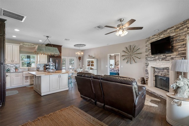 living room featuring a textured ceiling, dark wood-style flooring, a fireplace, and visible vents